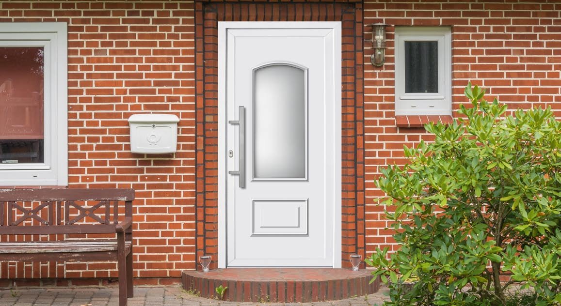 Białe drzwi wejściowe PCV w klasycznym domu z cegły